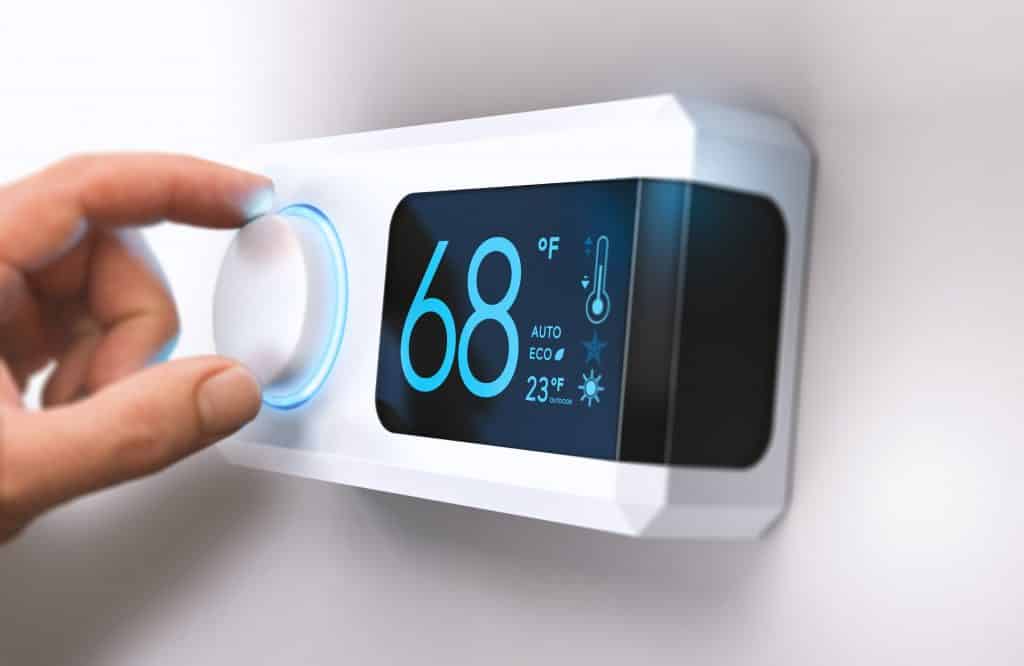 hand adjusting temperature on smart digital thermostat
