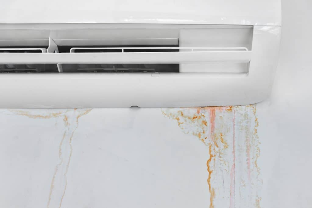 Mold stains on a wall underneath a leaky air conditioning unit